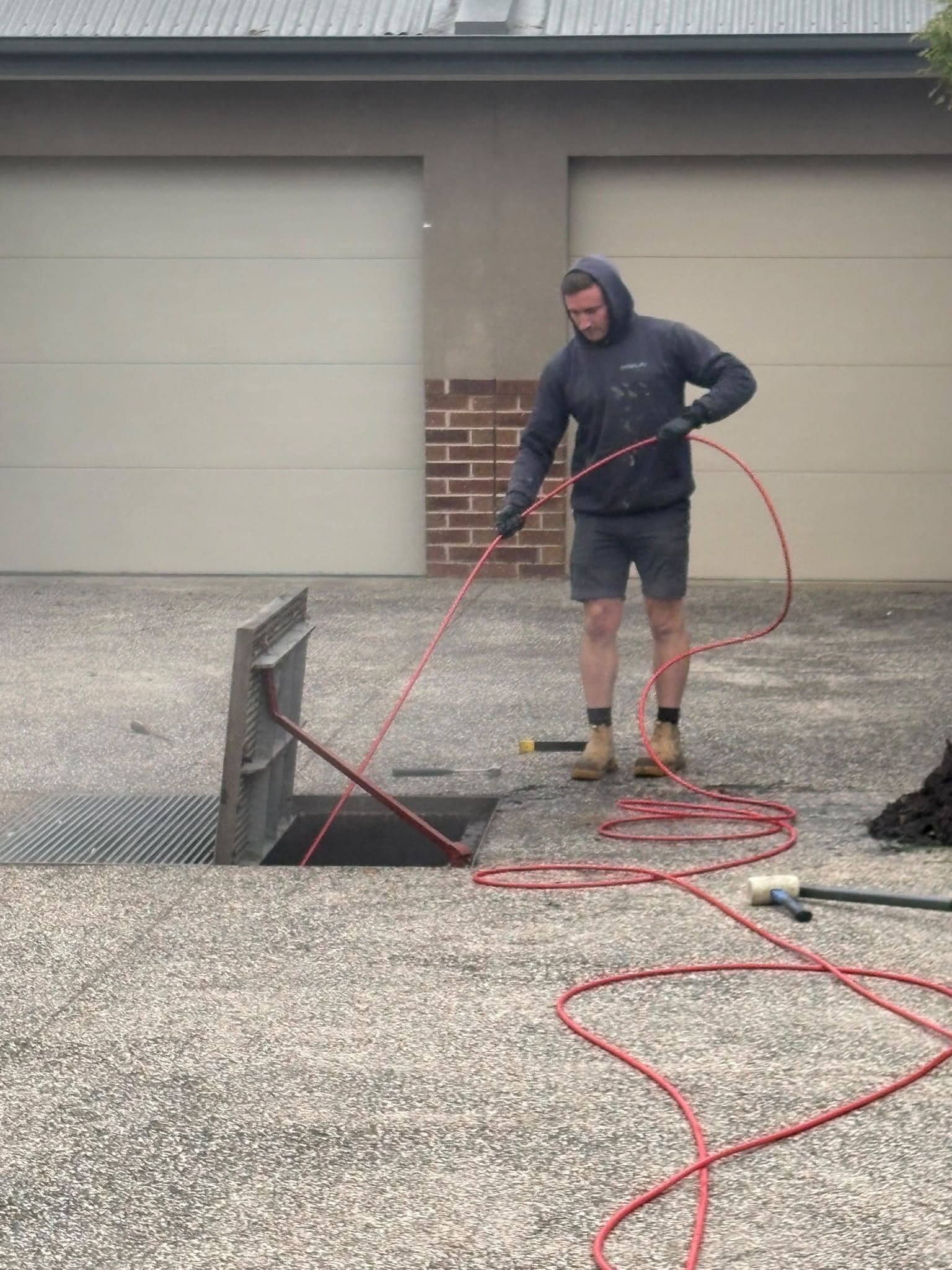 Prava plumber jetting a blocked stormwater drain on a residential driveway