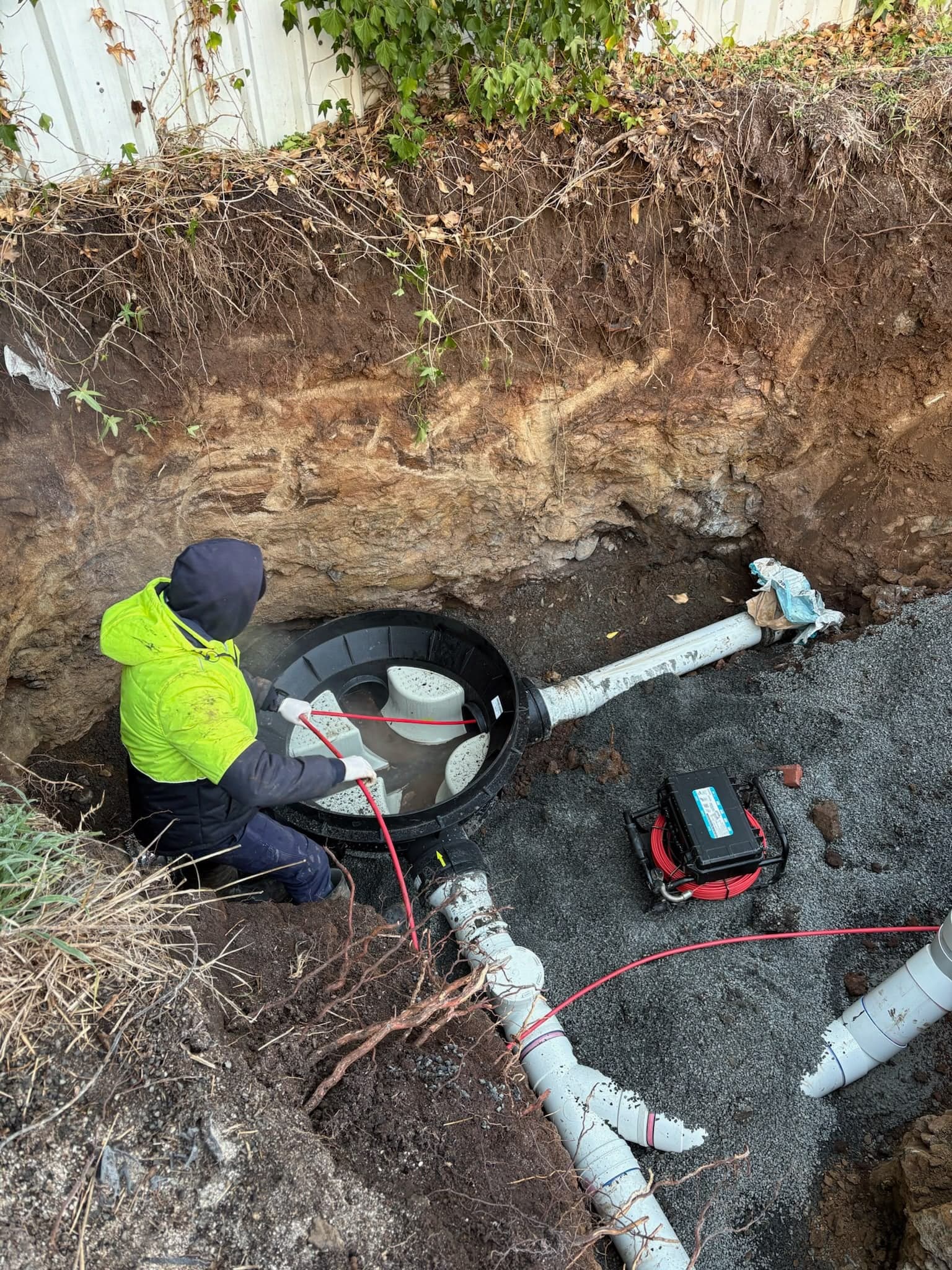 Prava plumber connecting new pipework to a drainage pit while clearing a blocked drain