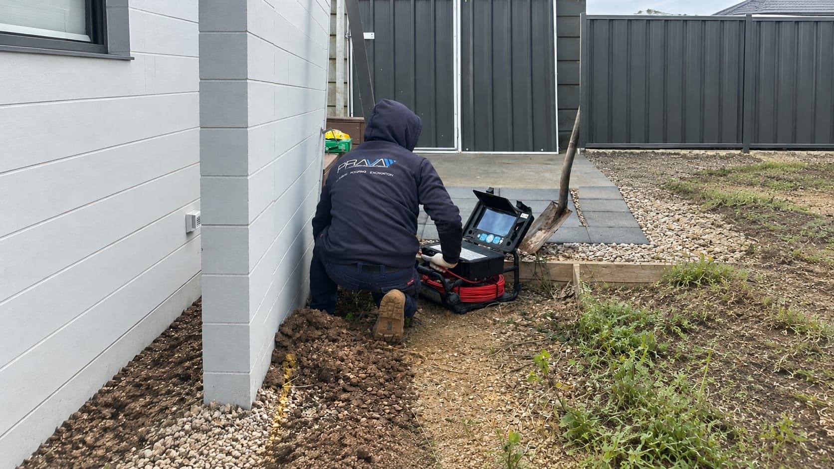 Prava technician setting up a CCTV drain camera beside a house