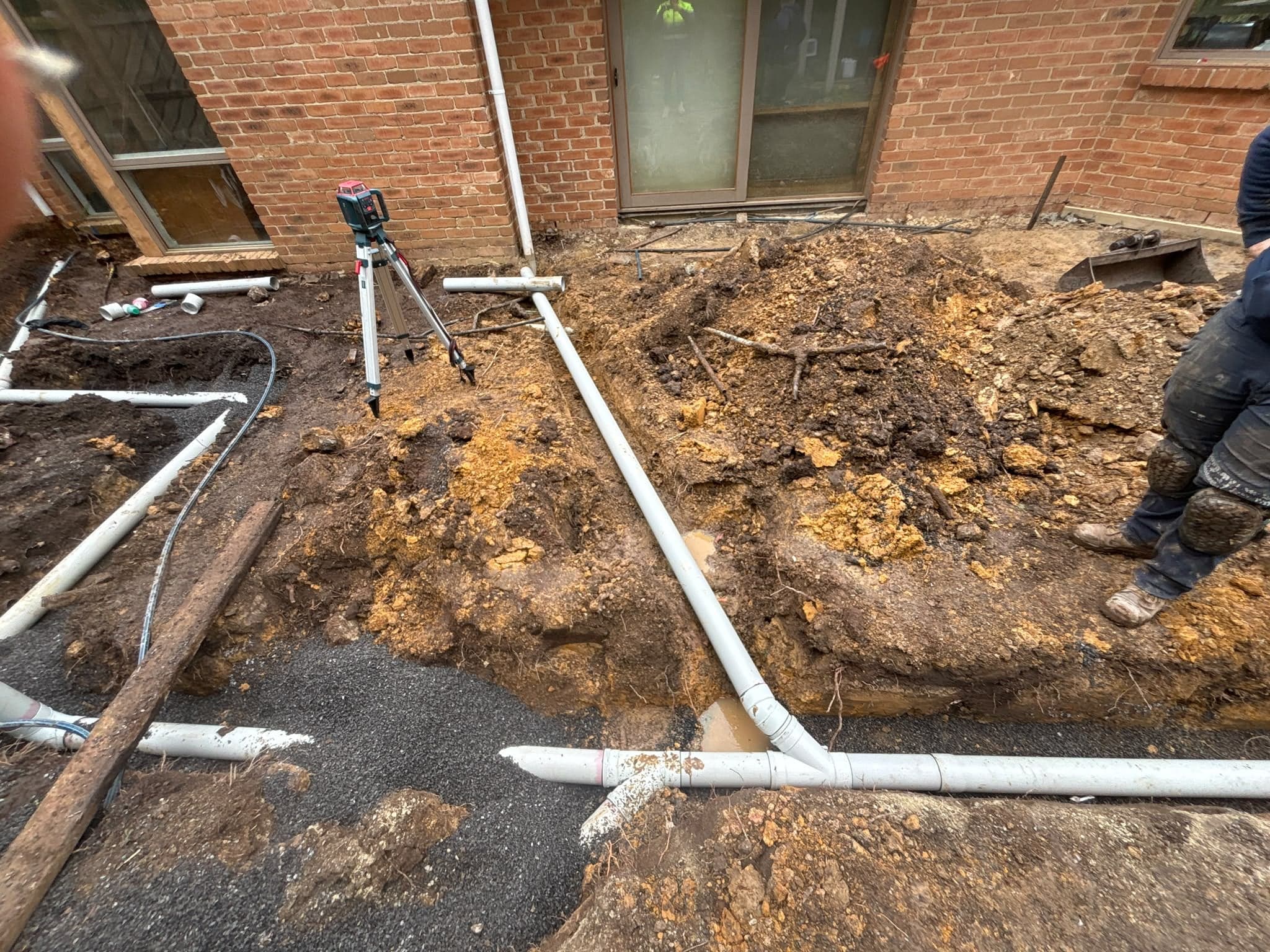 New PVC drainage pipework being laid beside a brick house