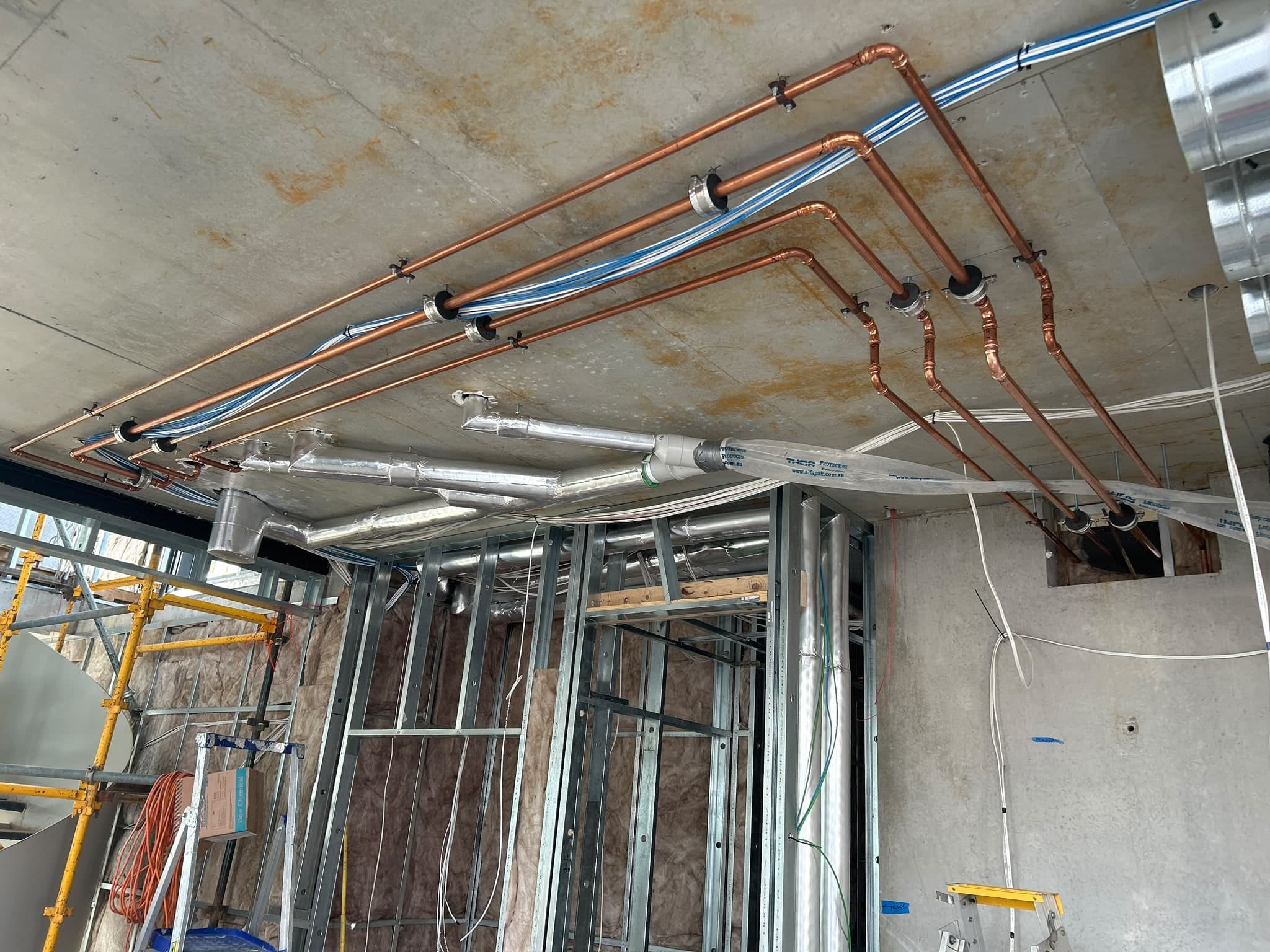 New copper gas and water lines run across the ceiling of a commercial fit-out