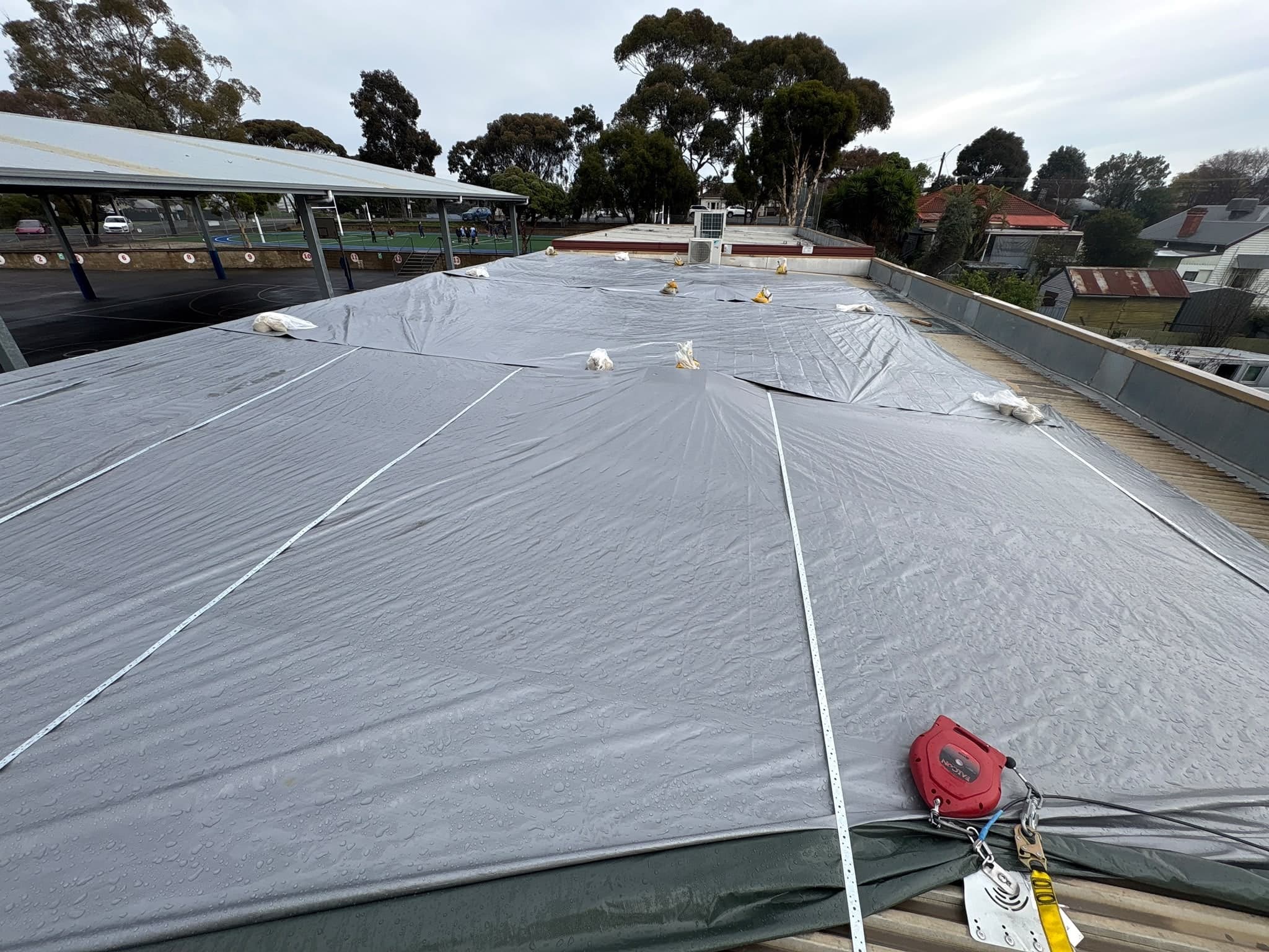 Damaged roof covered with a weighted tarpaulin as an emergency make-safe