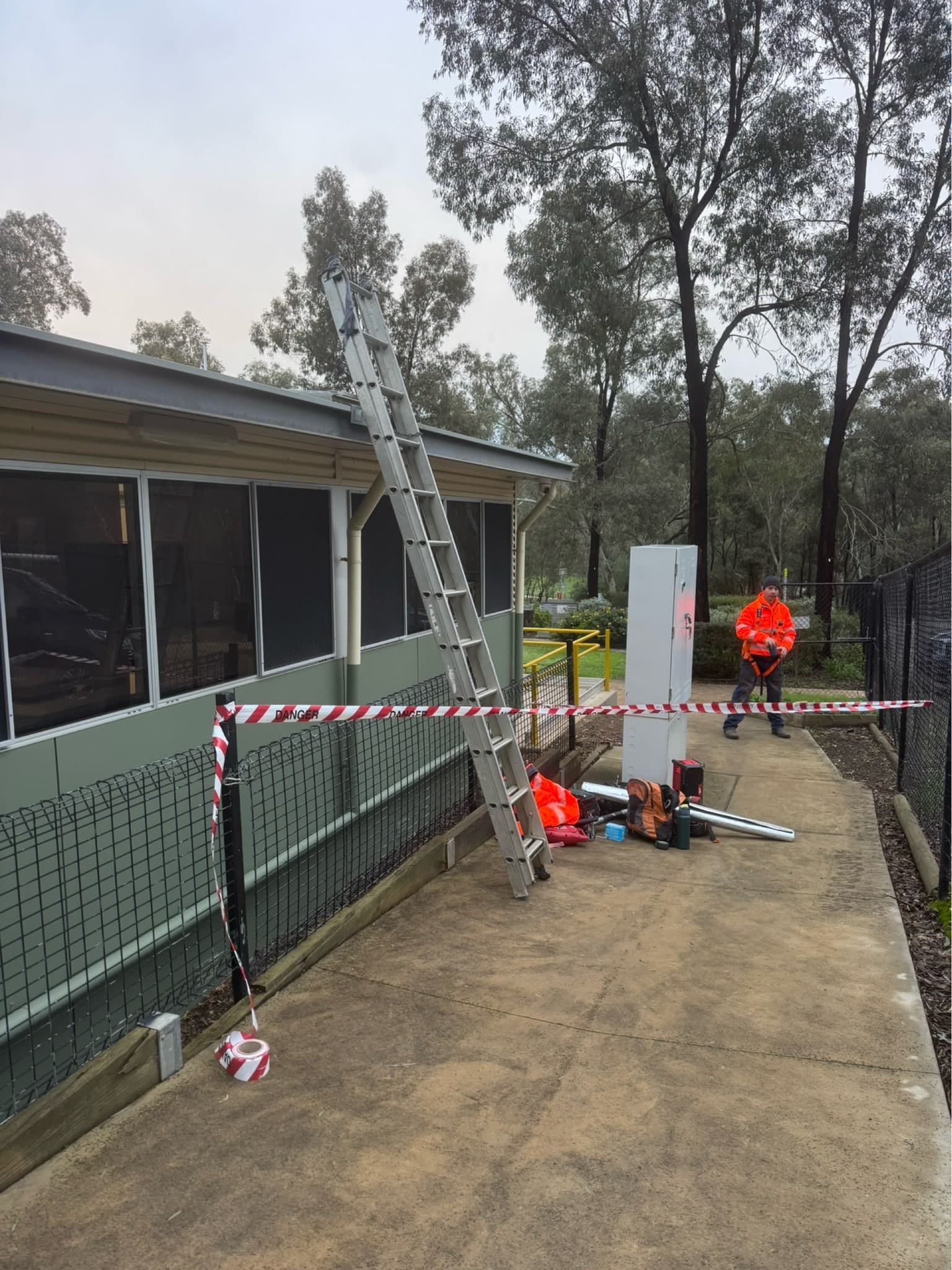 Make-safe site set up with barrier tape and a ladder at a damaged building