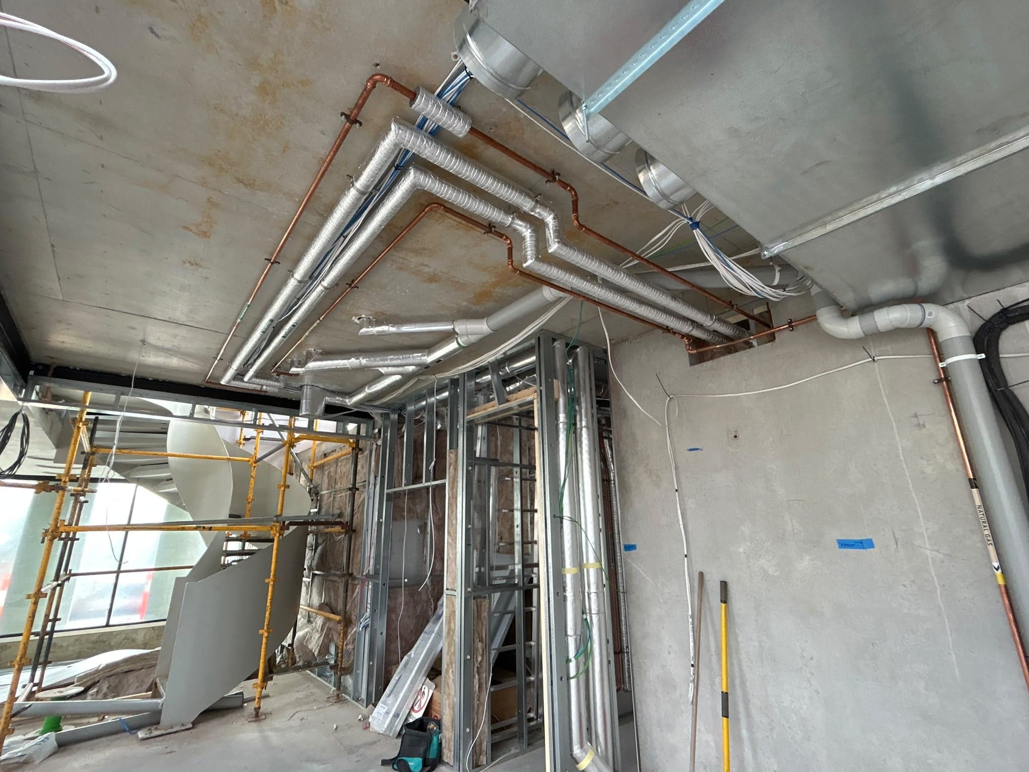 Lagged and copper pipework run across the ceiling of a commercial fit-out